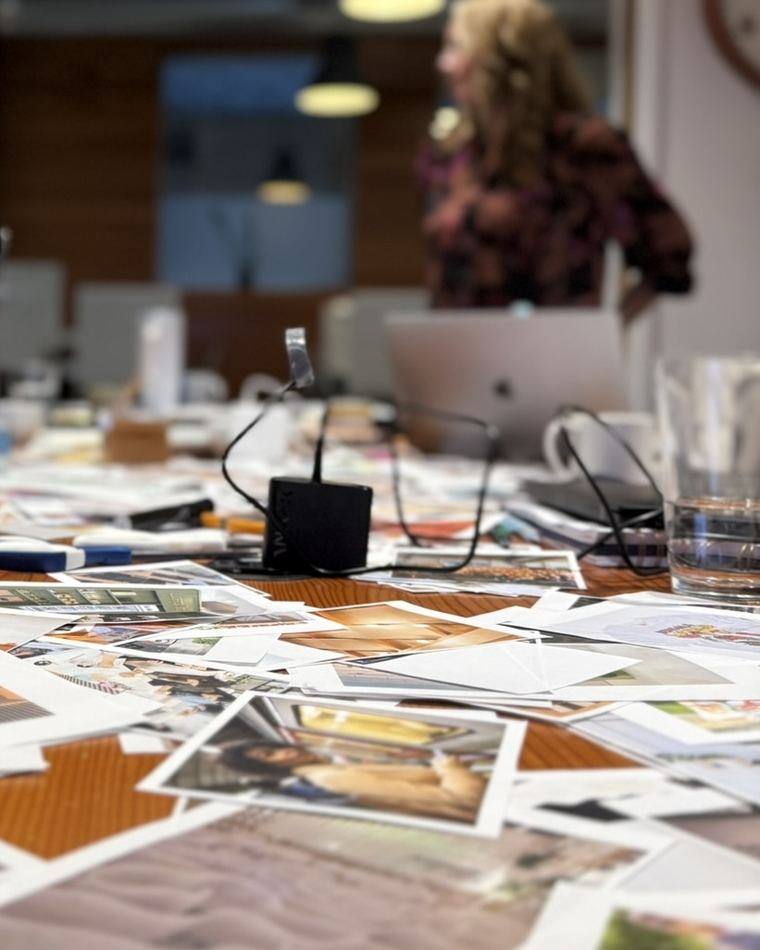 Customer research workshop for CX strategy Customer research photographs spread across a workshop table during a customer experience strategy session